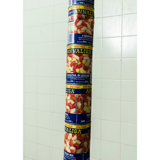 Exactly 30 cans of beans stacked on top of one another touching the floor and the ceiling